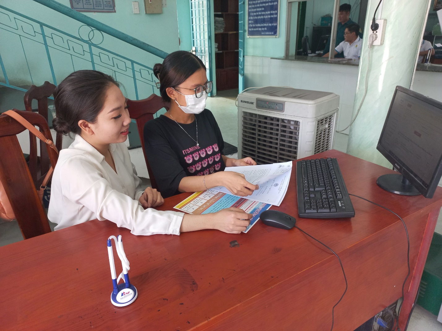 A couple of women looking at a paper

Description automatically generated